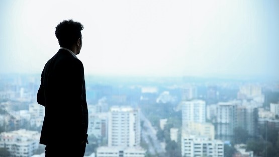 Mann im Anzug schaut von einem Hügel hinaus auf eine Stadt