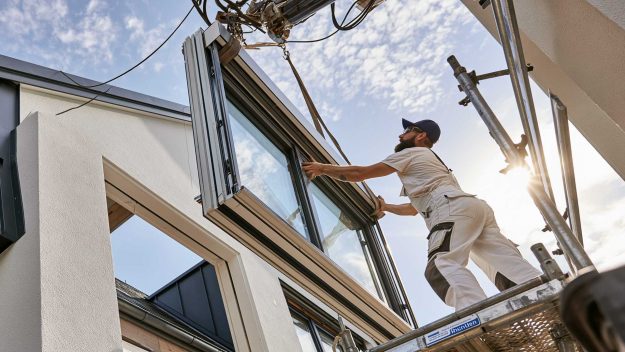 Handwerker bauen Fenster in Haus ein.